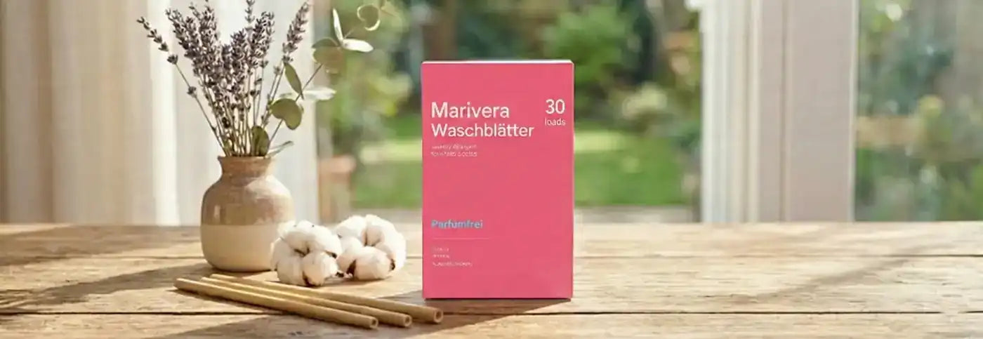 Umweltfreundliche Marivera Waschblätter in einer plastikfreien rosa Packung auf einem rustikalen Holztisch, dekoriert mit Baumwollblüten und Lavendel vor einem hellen Gartenhintergrund.